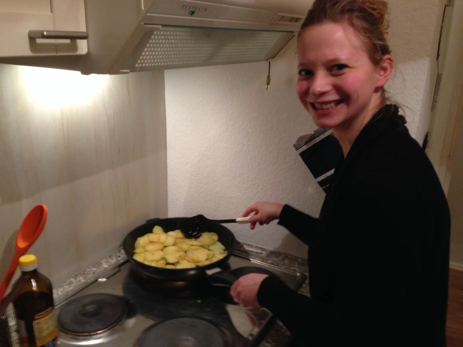 Anna smiling at the camera while frying potatoes in a pan